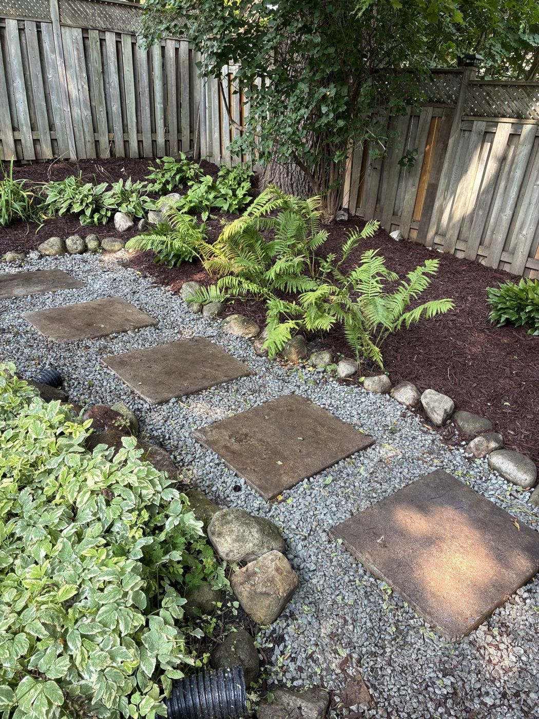 Stepping-stone path through pea gravel with freshly mulched garden beds
